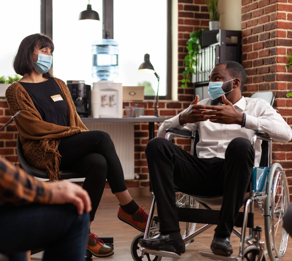 Man with disability talking at group therapy session with people having alcohol addiction